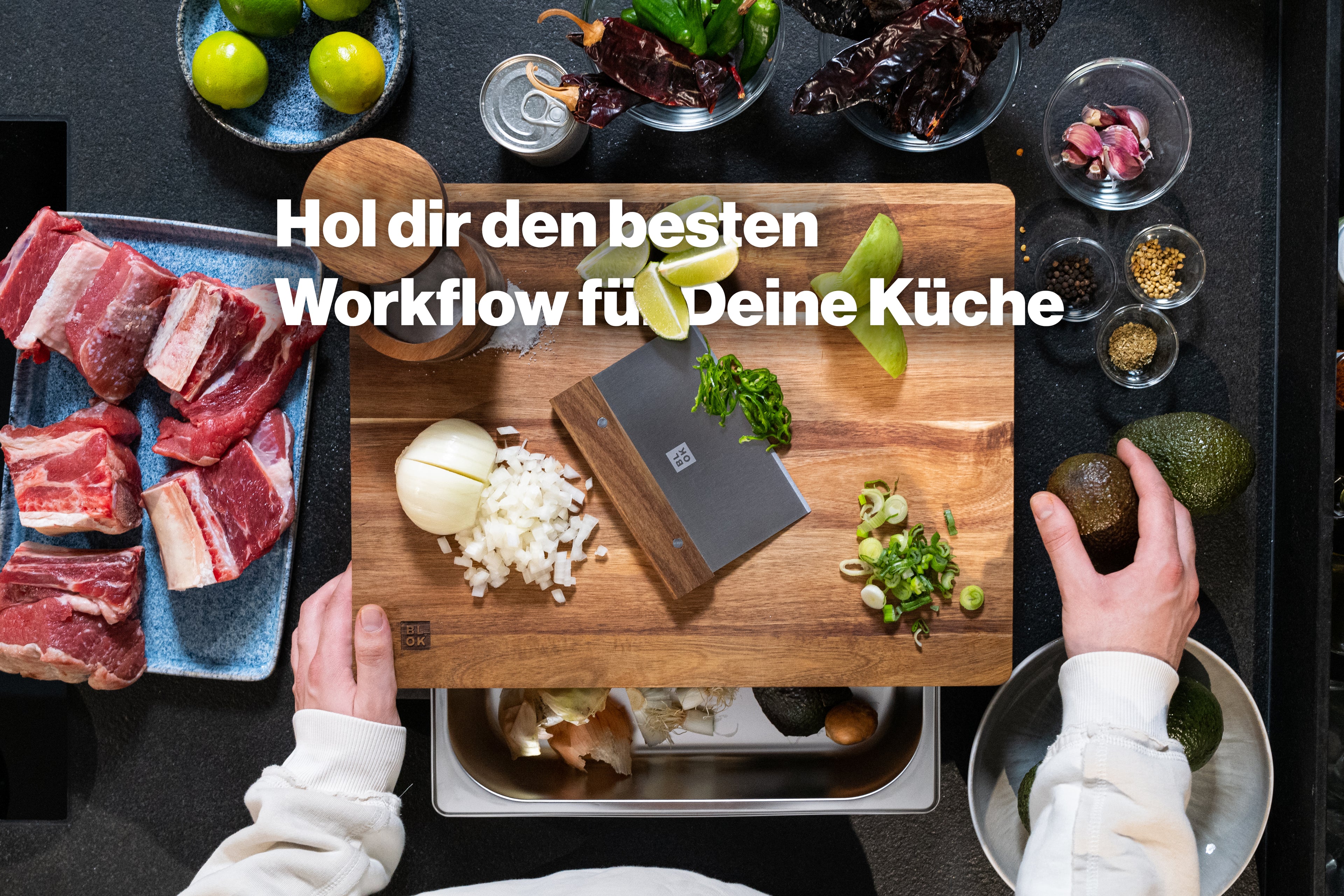 Vogelperspektive auf eine moderne Küchenszene mit Zutaten und Schneidebrett. In der Mitte befindet sich ein Holzbrett mit geschnittener Zwiebel, Frühlingszwiebeln, Limettenstücken und einem Edelstahl-Holz-Küchenwerkzeug. Links liegt rohes Fleisch auf einem blauen Teller, rechts befinden sich Gewürze, Avocados und Knoblauch. Eine Person hält links das Brett, eine andere greift rechts nach einer Avocado. Darüber steht in weißer, fetter Schrift: „Hol dir den besten Workflow für Deine Küche“.